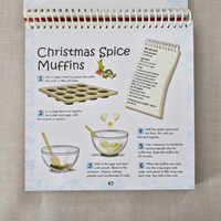 Recipe card for Christmas Spice Muffins with illustrations and text on a textured surface