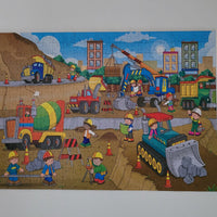 Children's puzzle with a construction scene featuring trucks and workers.