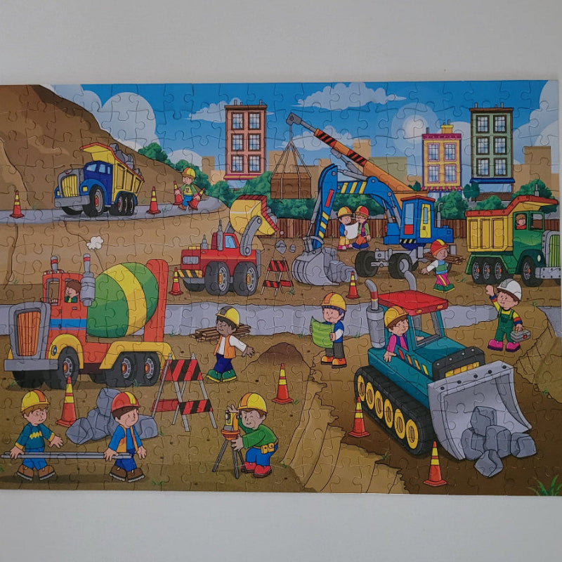 Children's puzzle with a construction scene featuring trucks and workers.