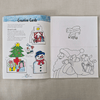 Open book with Christmas-themed colouring pages/cards and instructions on a textured surface