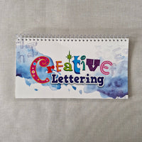 Notebook with 'Creative Lettering' design on a textured surface