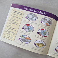Open book with a recipe for 'Crustless Corn Quiche' on a gray surface