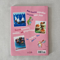 Pink book back with text, 'Make beautiful cupcakes and pretty cake pops' on a textured gray surface