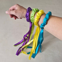 Colorful ribbon bracelets on a person's wrist against a neutral background