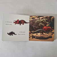 Childrens book with dinosaur illustrations and text on a textured surface