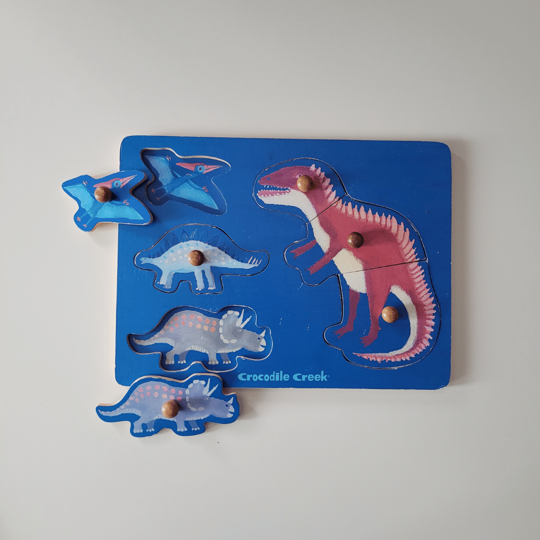 Wooden dinosaur puzzle with blue board and colorful dinosaur figures on a white background