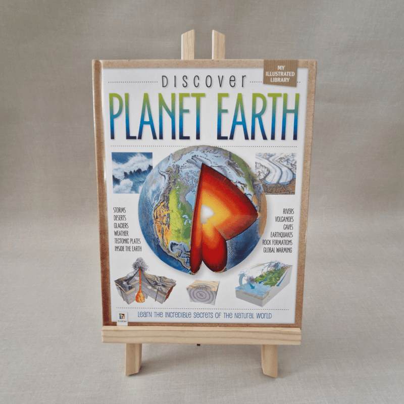 Book titled 'Discover Planet Earth' on a wooden stand against a neutral background
