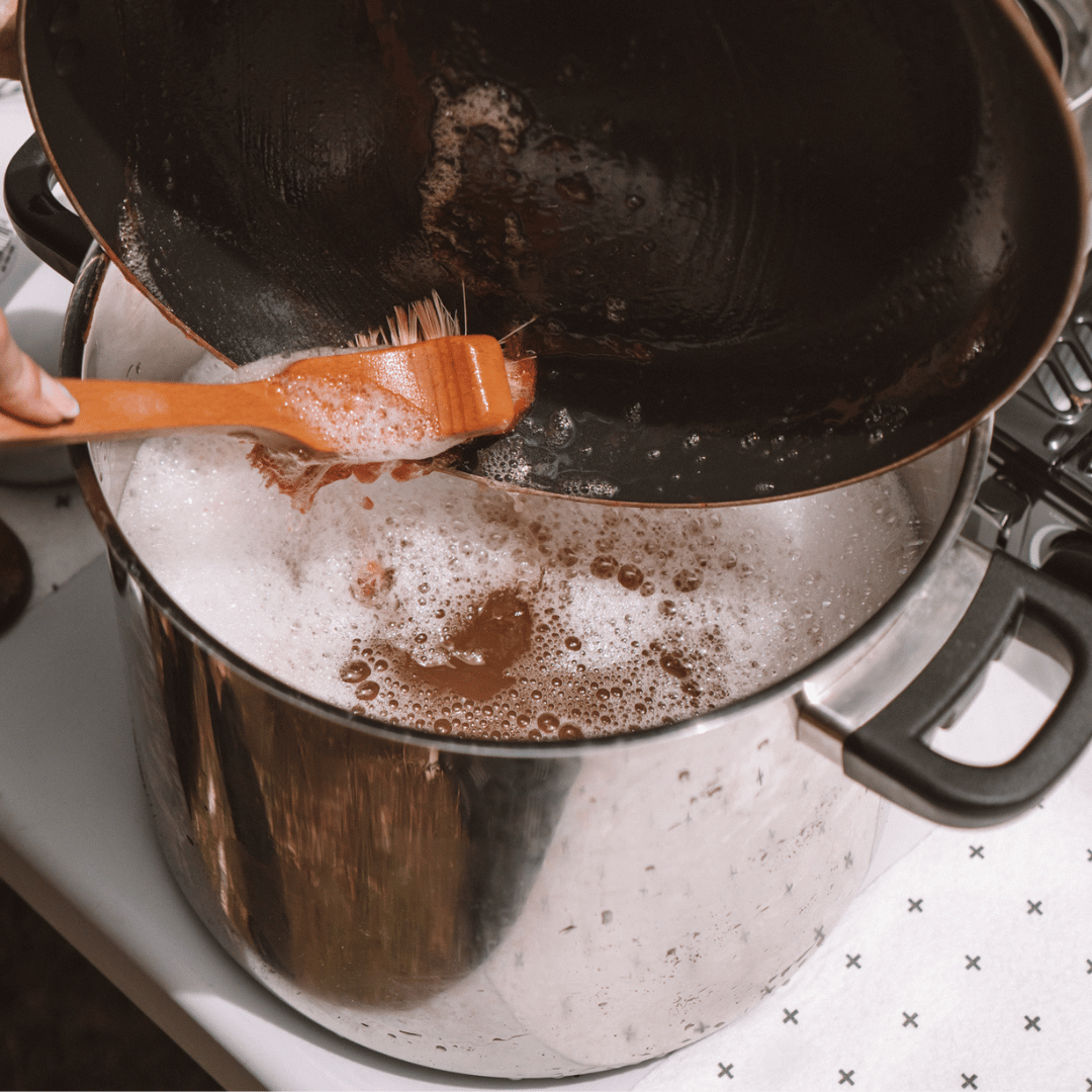 Person scrubbing a pot with a brush using a cleaning solution.