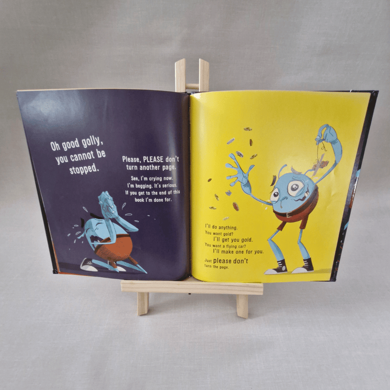 Open book with colourful illustrations of a blue creature on a grey background