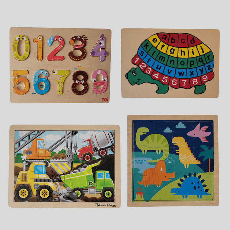Set of four wooden puzzles with numbers, letters, construction vehicles, and dinosaurs on a white background.