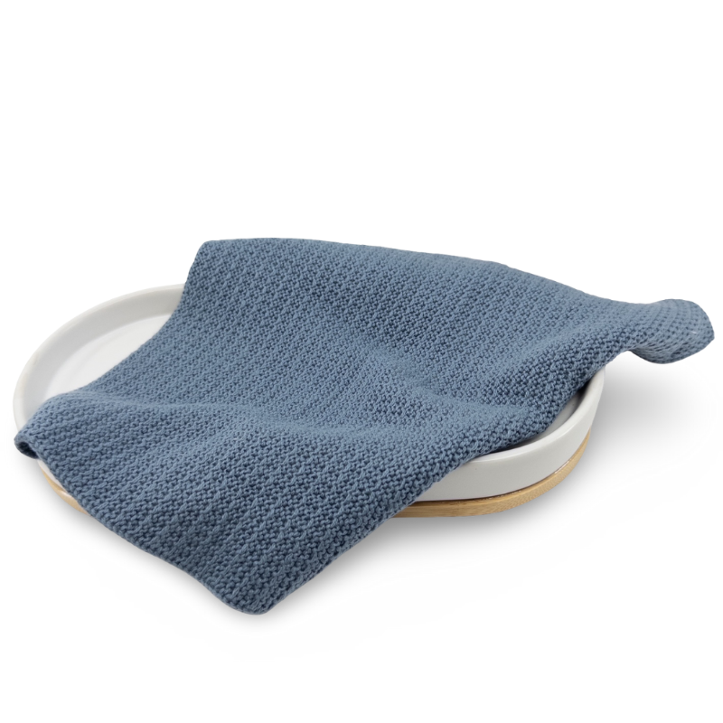 Denim Blue knitted organic cotton face cloth on a white plate with a white background