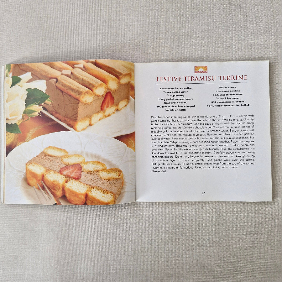 Open cookbook showing a recipe for 'Festive Tiramisu Terrine' on a textured surface.