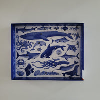 Jigsaw box with blue ocean-themed illustrations on a white background