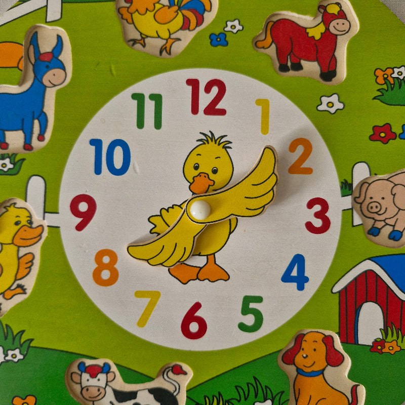 Children's wooden clock with colourful numbers and animal illustrations on a green background