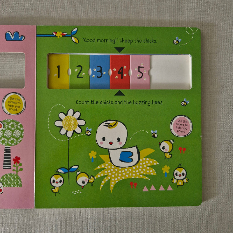 Open children's book with a green page featuring numbers and a cartoon character on a textured surface.