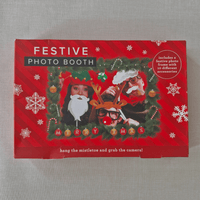 Festive photo booth set with Christmas-themed props on a red box.