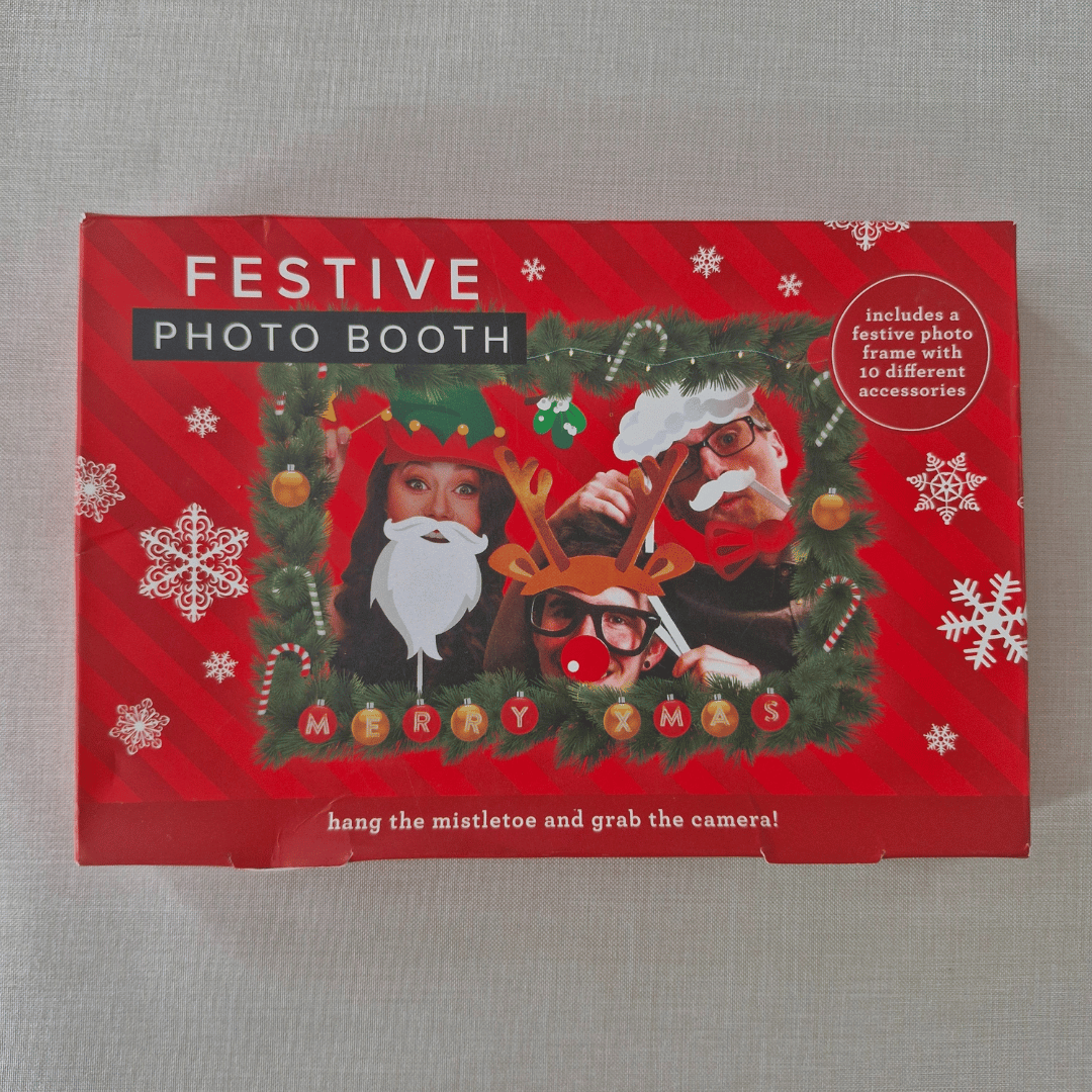 Festive photo booth set with Christmas-themed props on a red box.