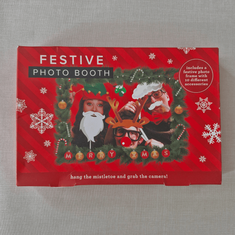 Festive photo booth set with Christmas-themed props on a red box.