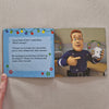 Open book showing fireman sam character and text on a beige surface