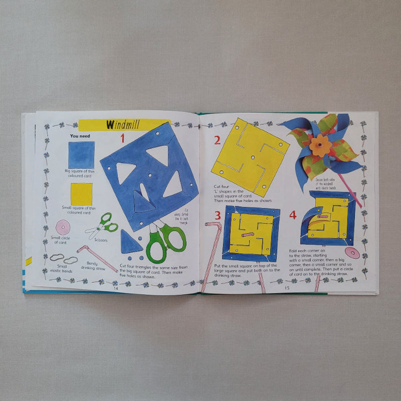 Open book with illustrations to make a paper windmill on a plain background