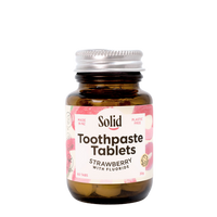Bottle of Solid Toothpaste Tablets with strawberry flavor on a white background