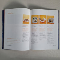 Open cookbook showing recipes with images of food on a neutral background