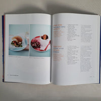 Open book with food images and text on a gray surface