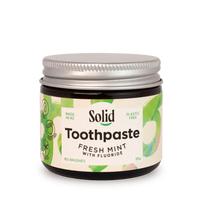 Jar of solid toothpaste with a white background