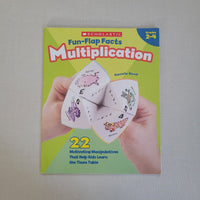 Book cover of 'Scholastic Fun Flap Facts Multiplication' with a hand holding a multiplication flap book on a gray background.