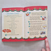 Open book with Christmas-themed pages on a grey surface
