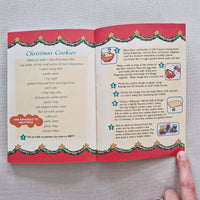 Open book with Christmas-themed pages on a grey surface