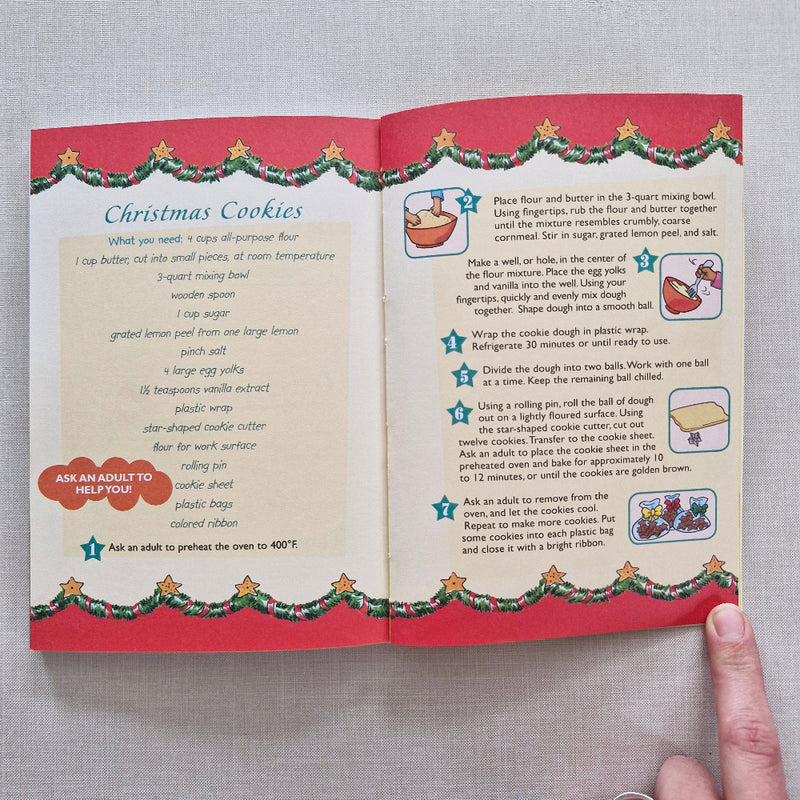 Open book with Christmas-themed pages on a grey surface