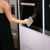 Person cleaning front of wall oven with a eco cloth