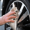 Person cleaning a car wheel with an eco cloth made of wood pulp and cotton