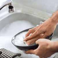 Person washing a frying pan with a sponge in a sink