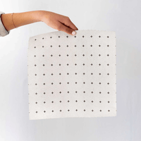 Hand holding a reusable bamboo towel with black cross pattern on a light gray background