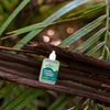 Small bottle of 'insect repellent' product on a branch with green leaves in the background
