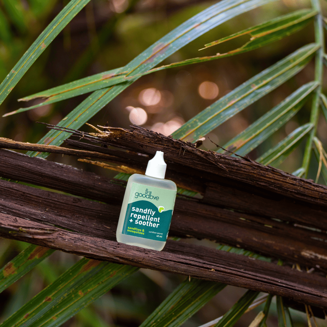 Small bottle of 'insect repellent' product on a branch with green leaves in the background