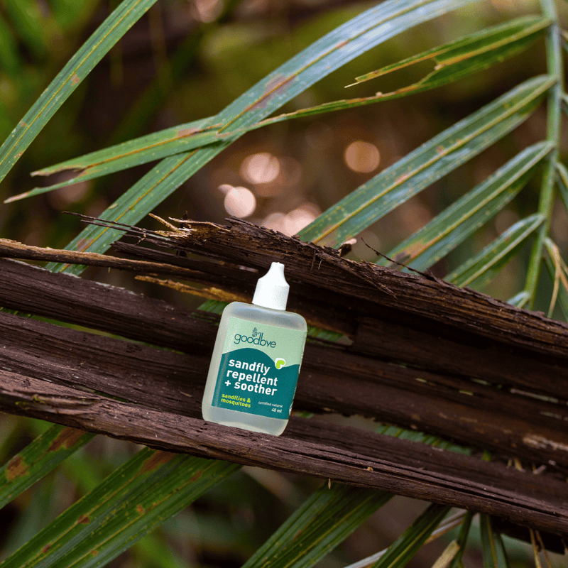 Small bottle of 'insect repellent' product on a branch with green leaves in the background