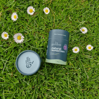 Goodbye natural sunscreen container and lid on grass with daisies