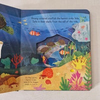 Open book with colourful underwater scene featuring hermit crabs, starfish, and fish.