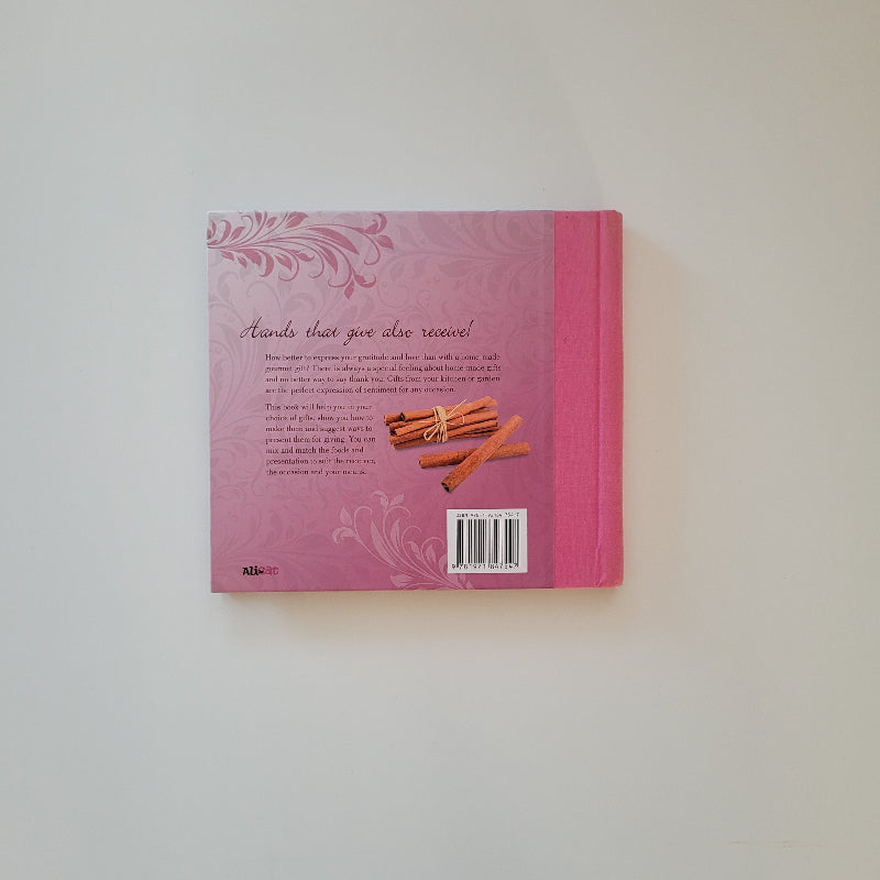 The back cover of a pink cook book  featuring a  cinnamon sticks illustration, and elegant floral designs on a light gray background.