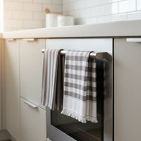 Set of two grey tea towels hanging on a oven door