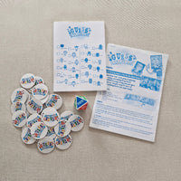 Guessing game components including cards, tokens, and a die on a beige surface