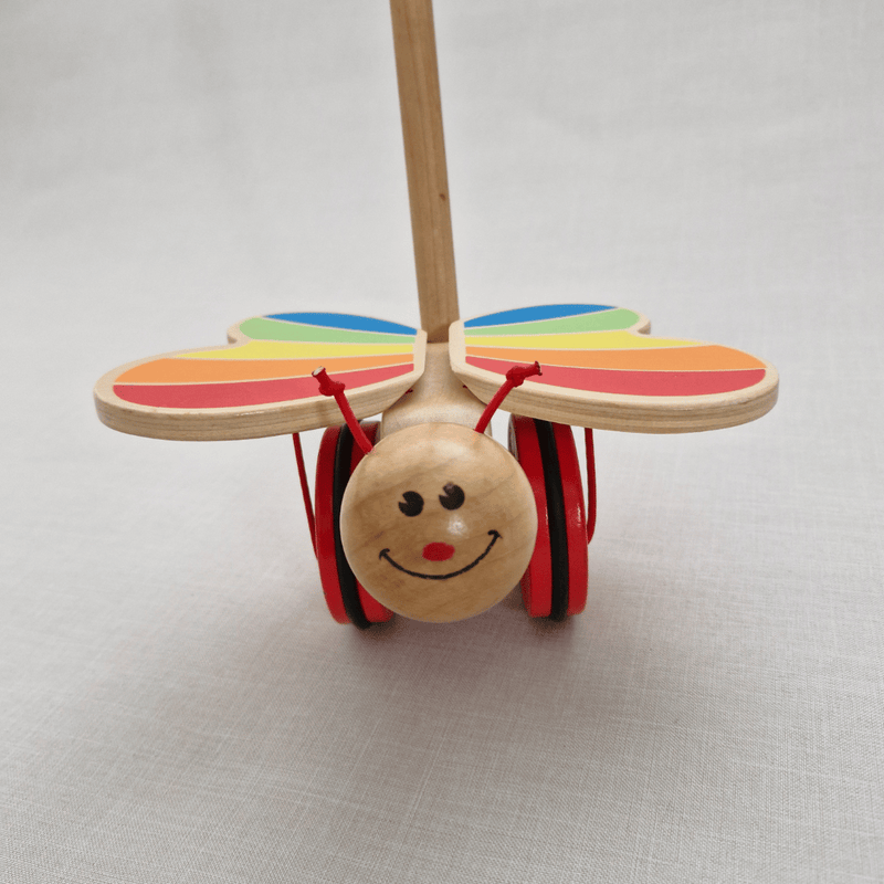 Wooden toy caterpillar with rainbow wings on a light gray background