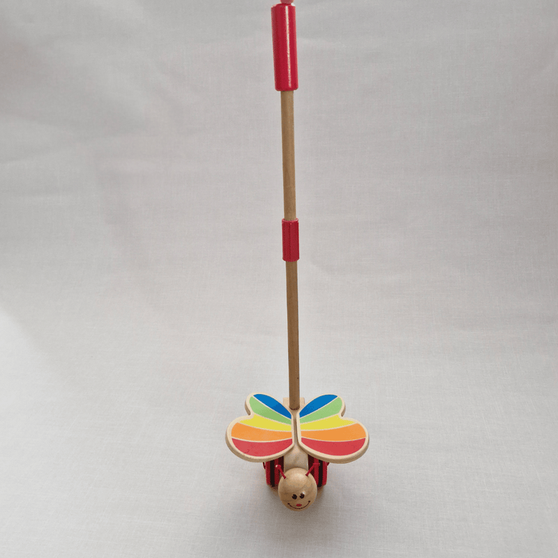 Toy with colorful butterfly wings and a red handle on a light gray background