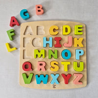 Wooden alphabet puzzle with colourful letters on a light grey background