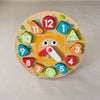 Colourful wooden clock toy with numbered and time-related pieces on a beige background