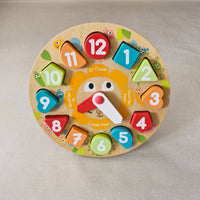 Colourful wooden clock toy with numbered and time-related pieces on a beige background