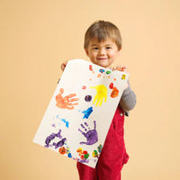 Child holding up a piece of paper showing their artwork using different paint colours
